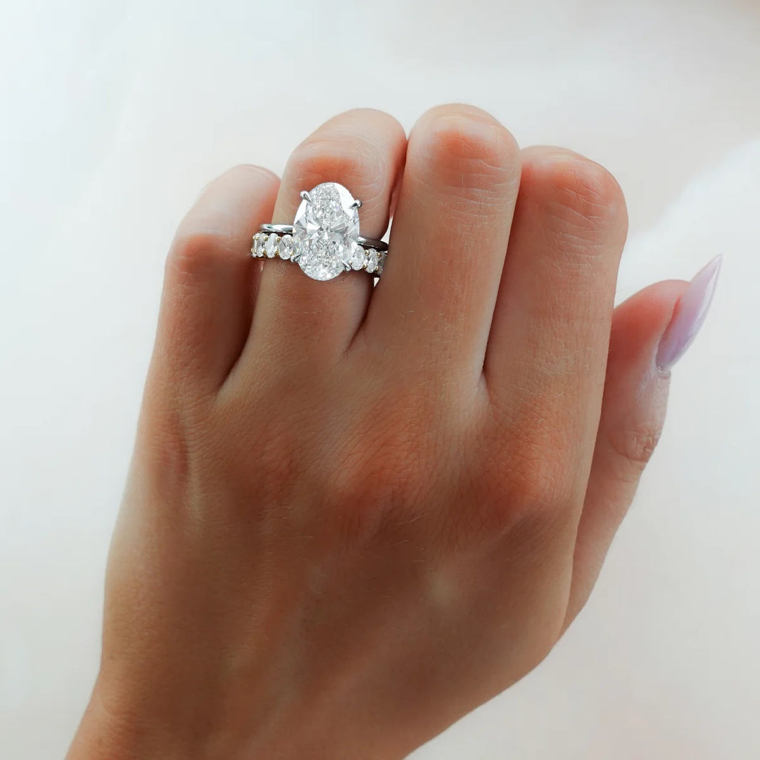2.50ct oval diamond engagement ring stacked with diamond eternity wedding band on hand, showing flush fit bridal set